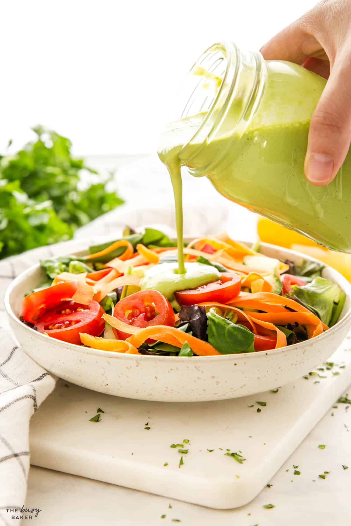 hand pouring salad dressing from a mason jar