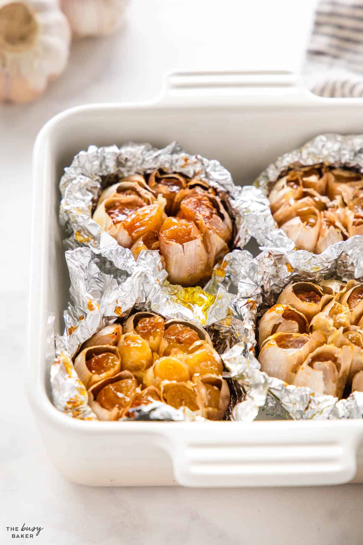 oven roasted garlic in a baking dish with aluminum foil