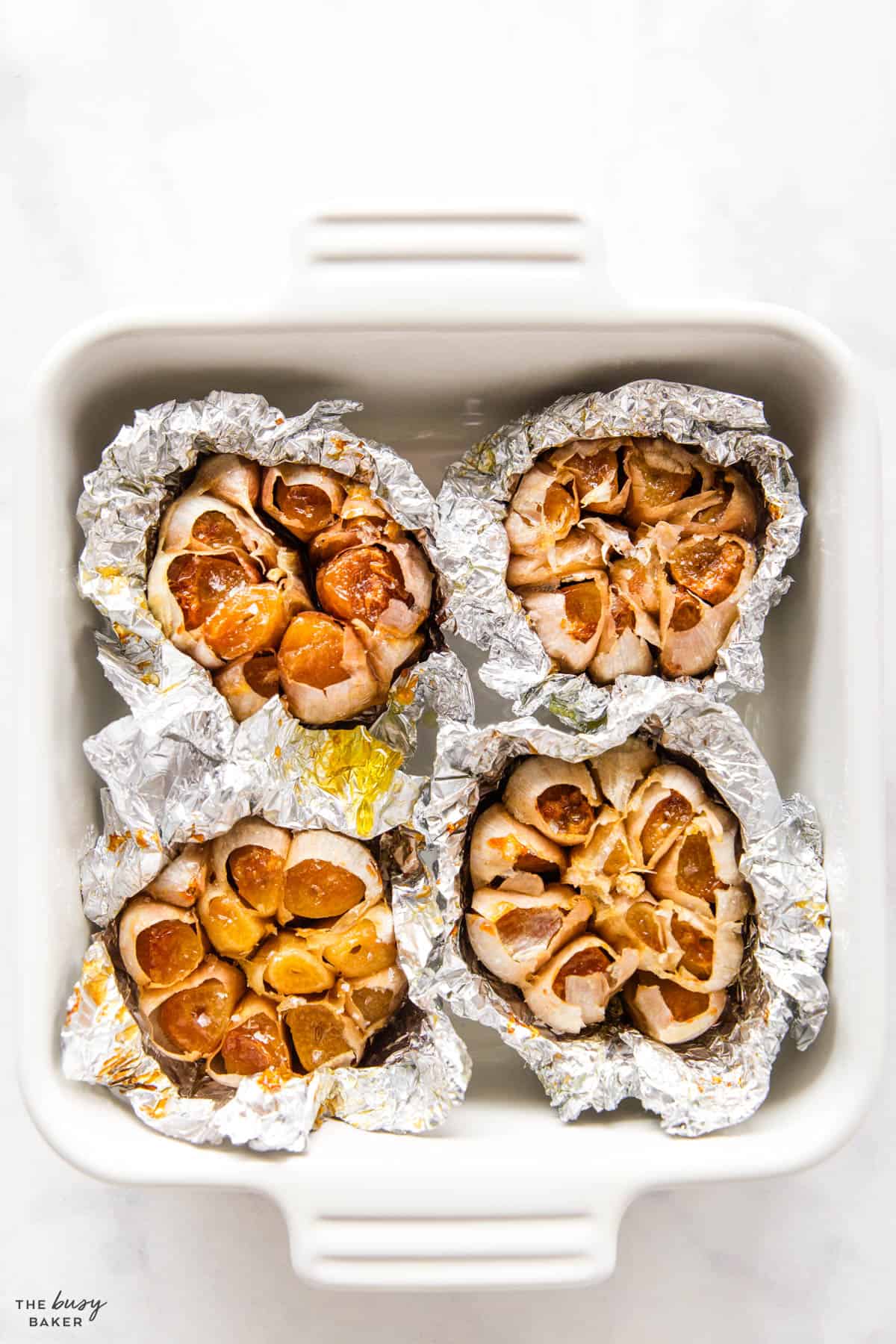 baking dish with oven roasted garlic in aluminum foil