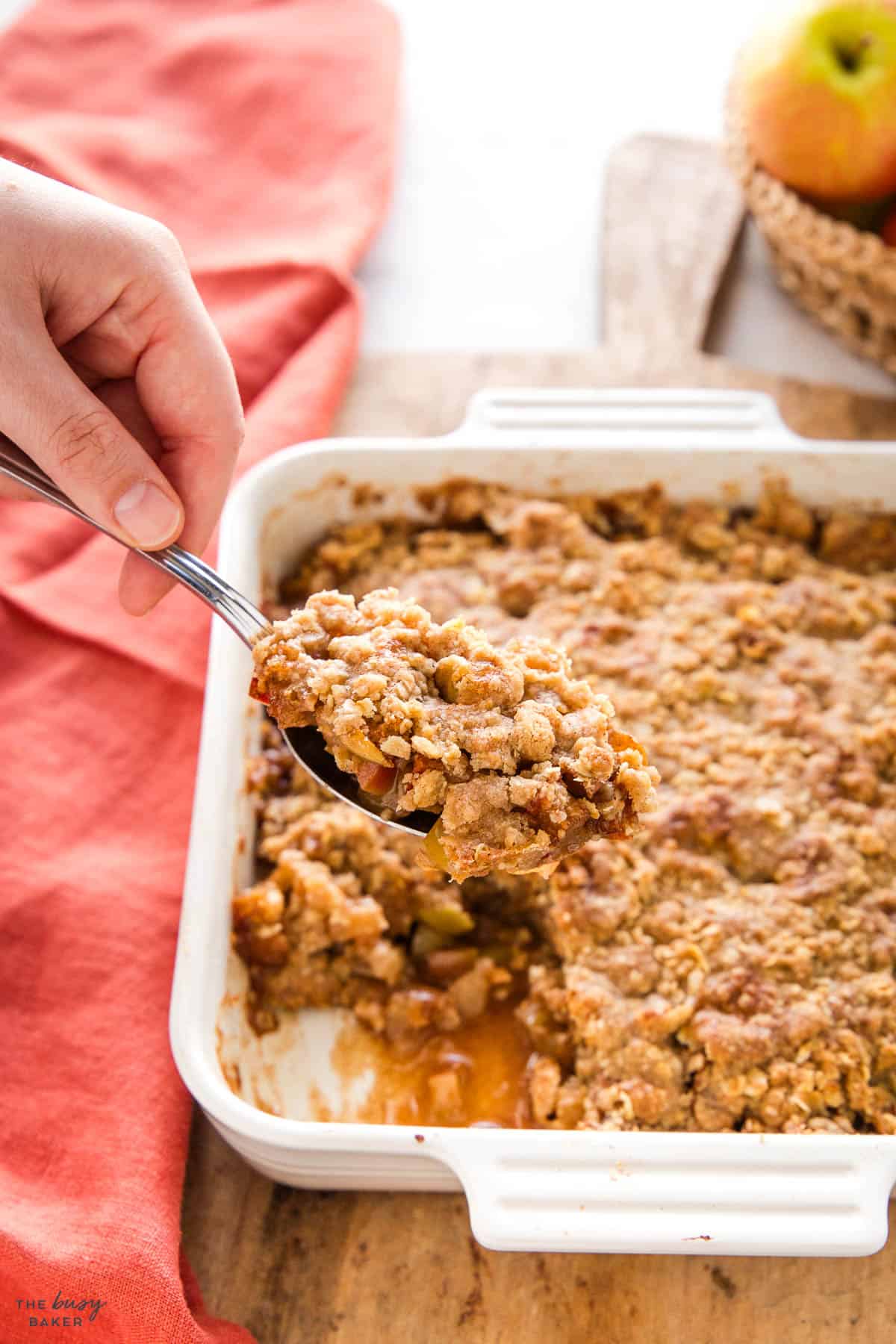 hand serving a spoonful of apple crisp