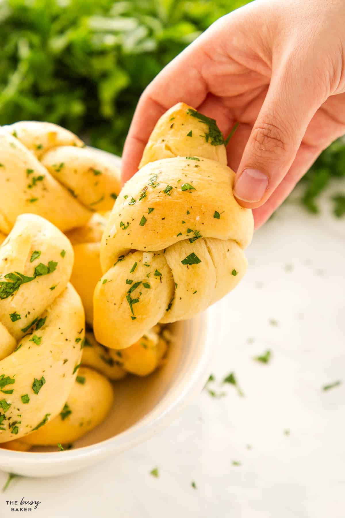 hand holding fluffy roll with butter and parsley and salt