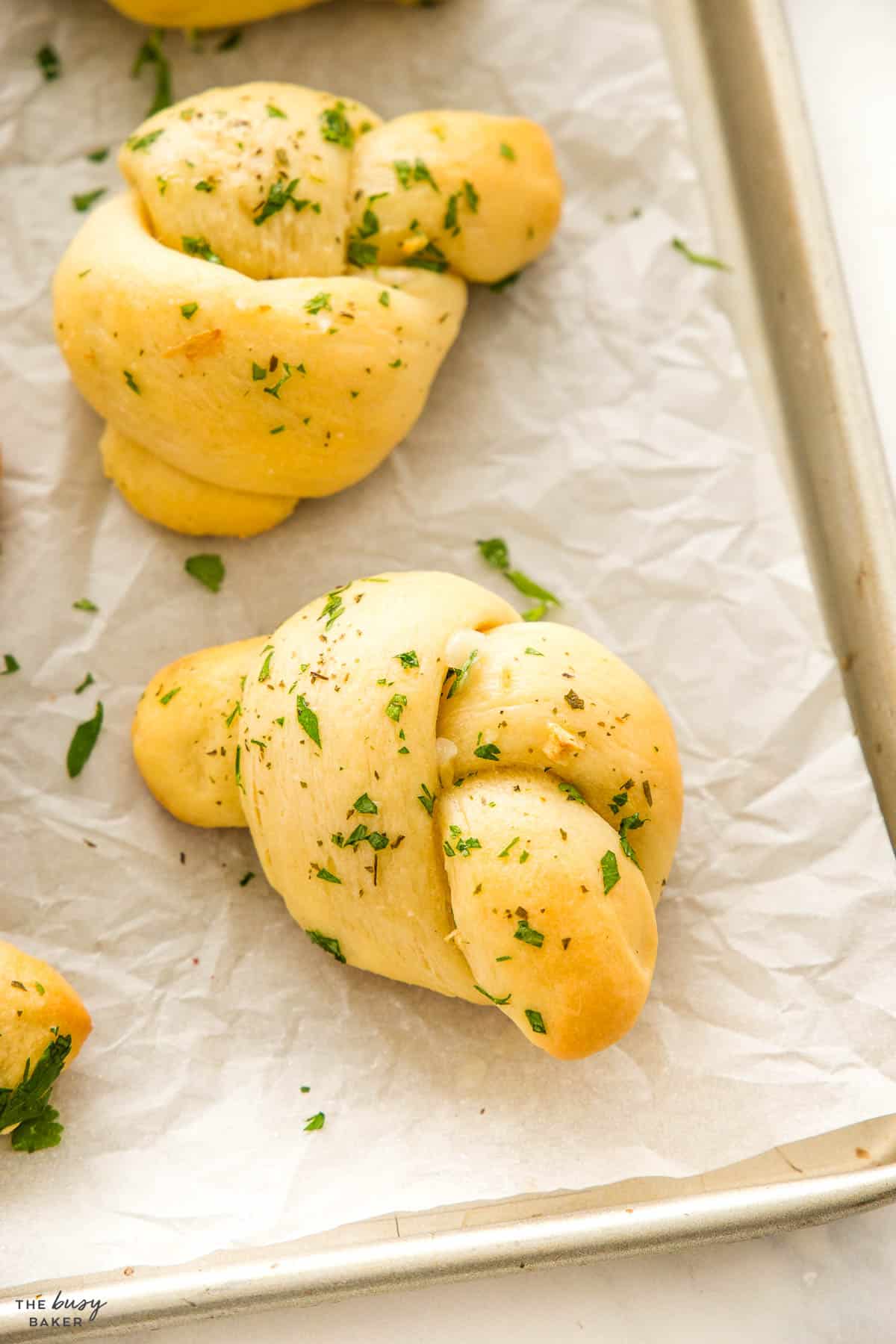 soft and fluffy garlic knots on a baking sheet with parsley