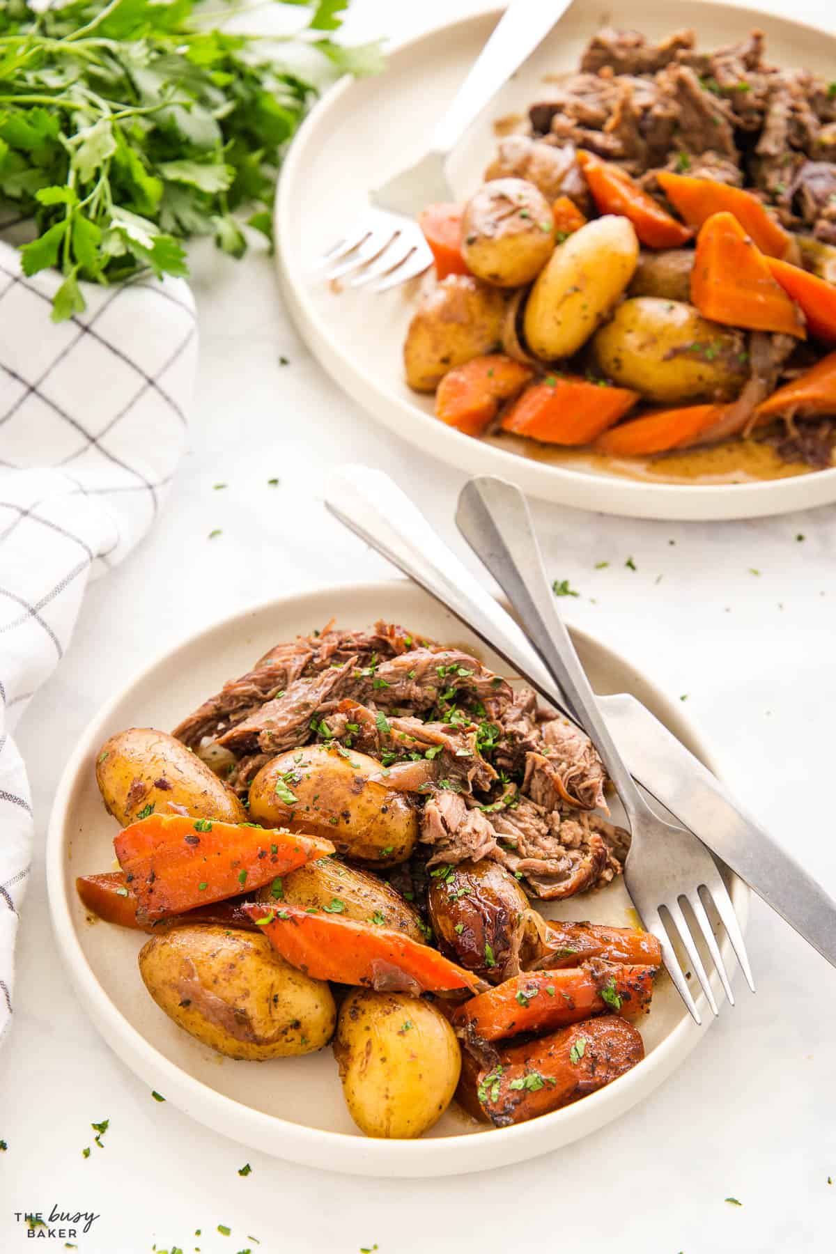 a plate of pot roast, gravy, potatoes and carrots