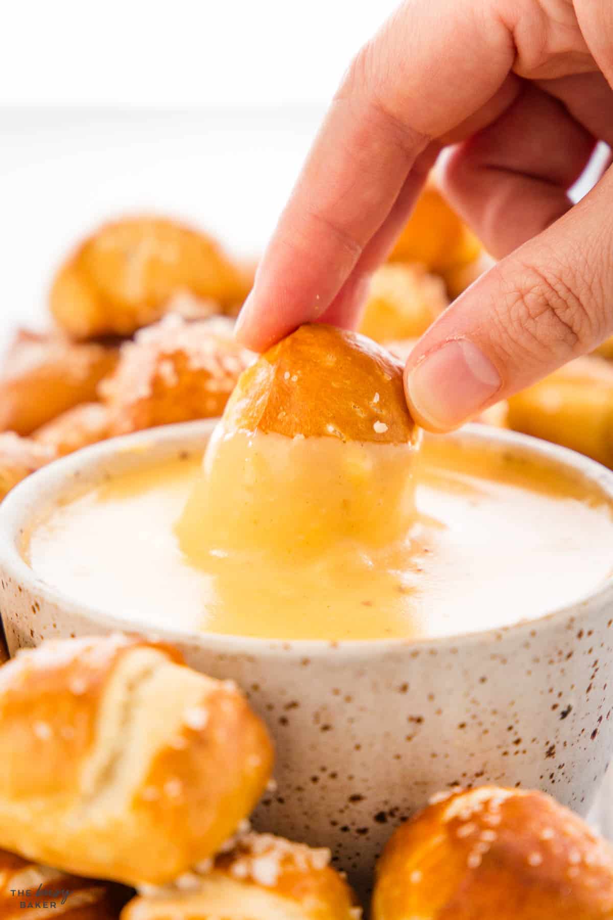 hand dipping an appetizer into cheese sauce