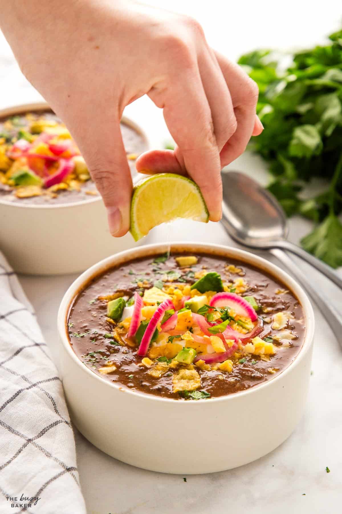 hand squeezing a lime into a bowl of soup