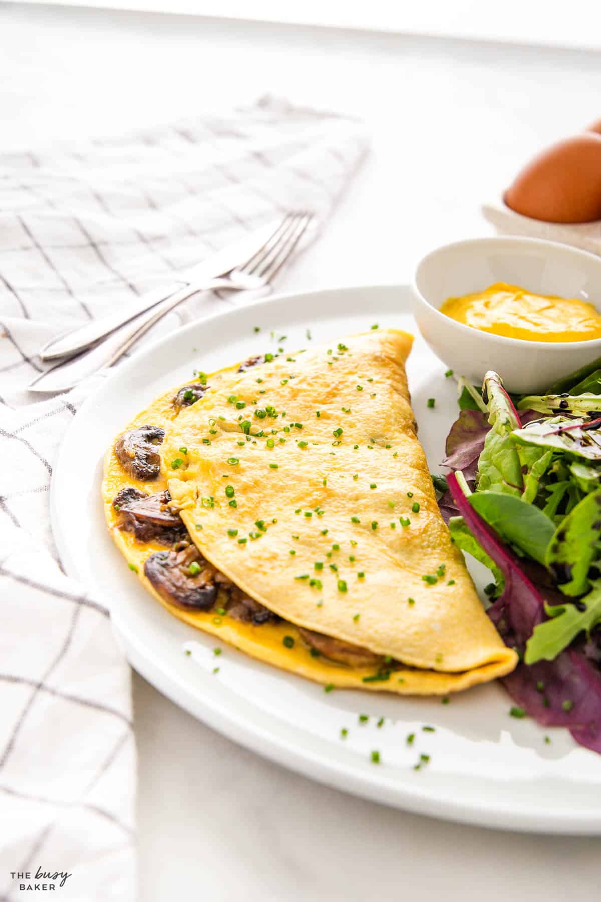 french omelette with a salad and mustard on a plate