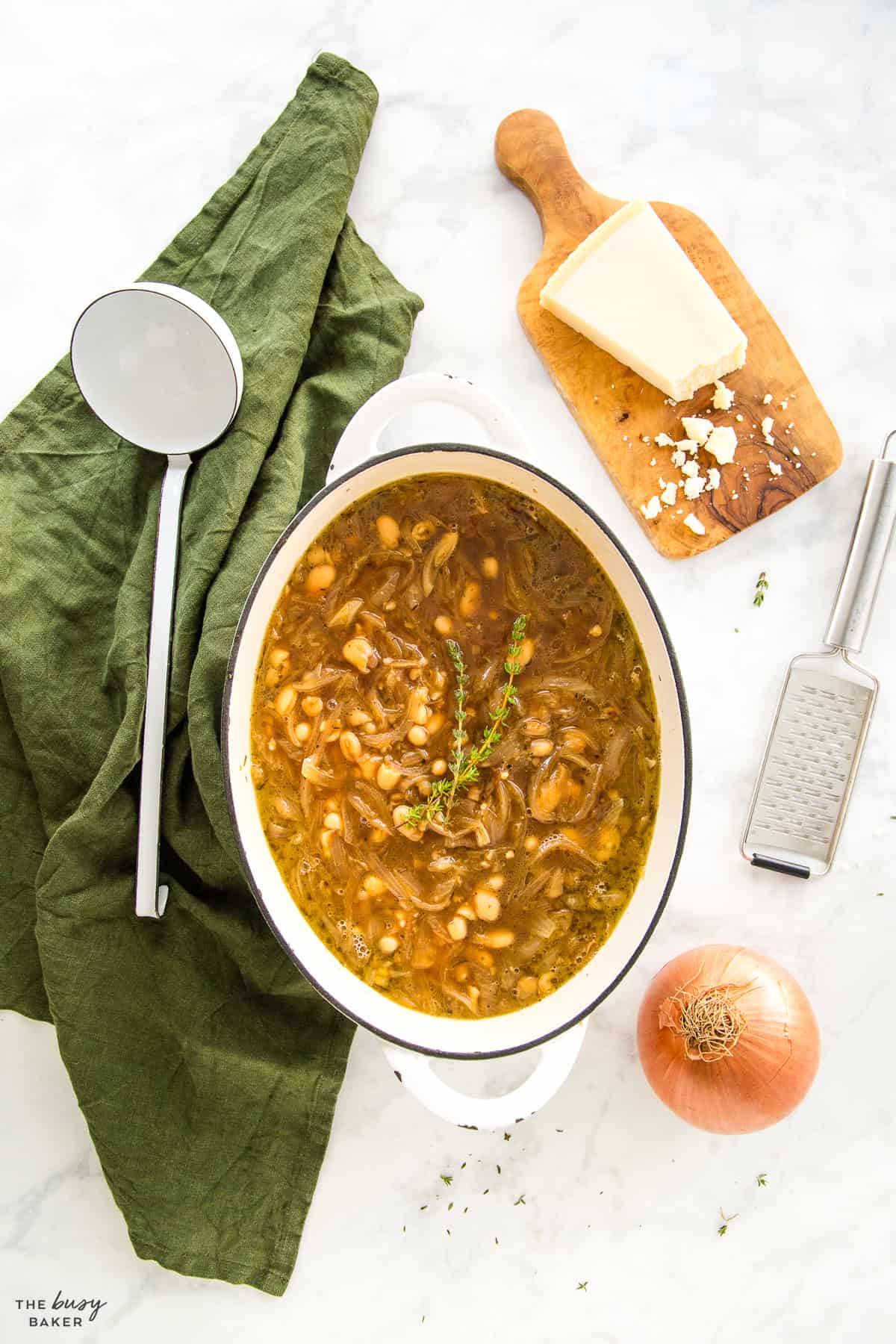 overhead image: white bean french onion soup in a white cast iron pot