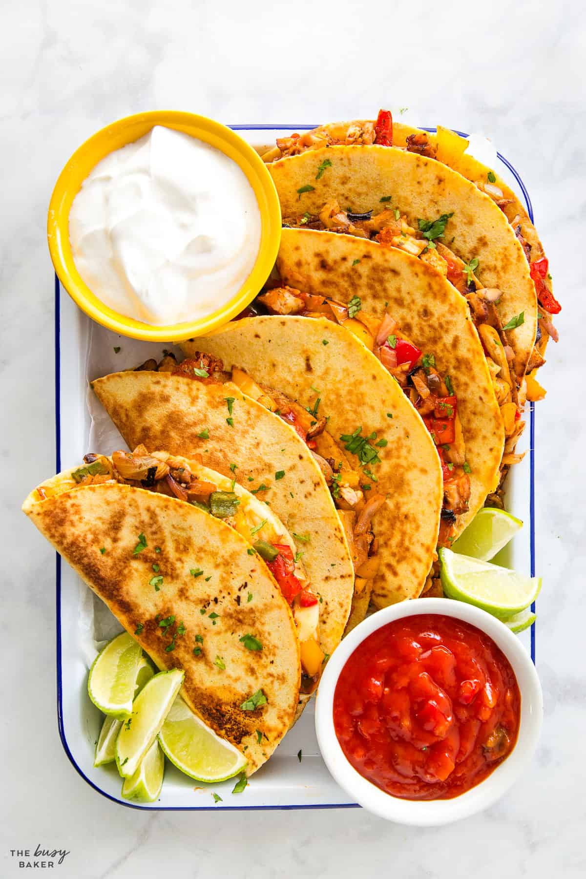 chicken quesadillas recipe with corn tortillas, peppers, salsa and sour cream with lime wedges