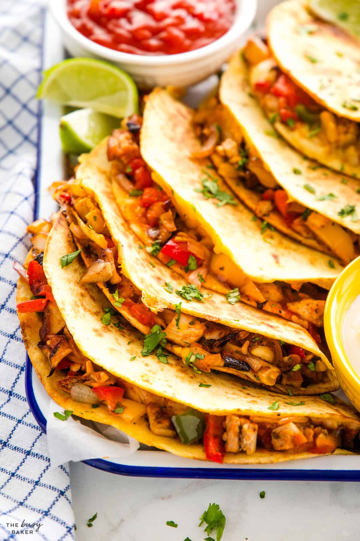 closeup image: how to make chicken quesadillas on a tray with salsa and lime