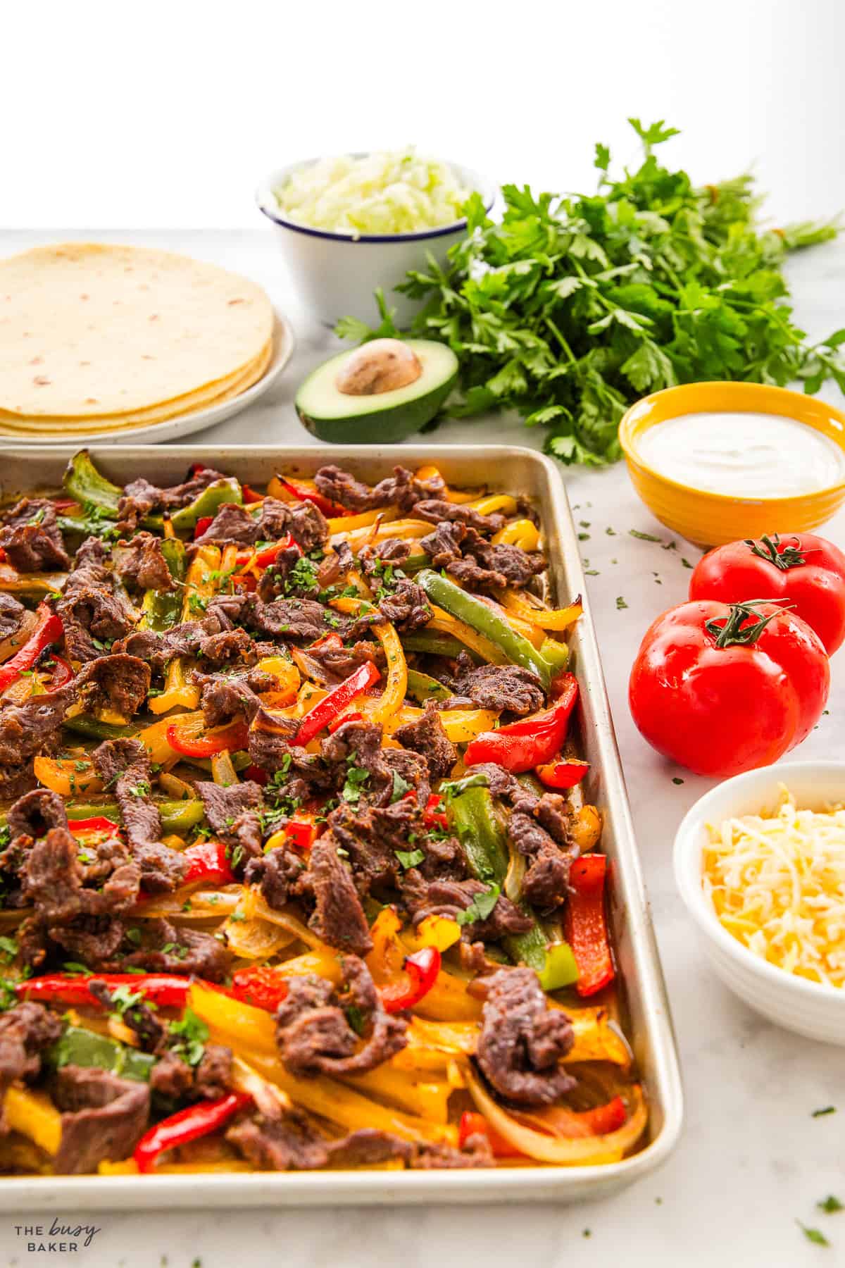 steak fajitas on a sheet pan with steak, peppers and onions