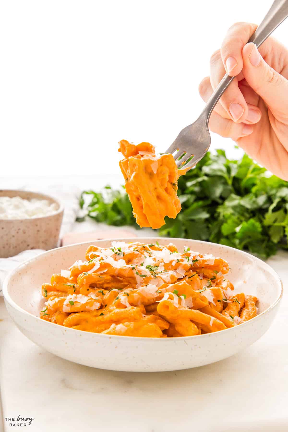 hand holding a fork with penne with rose sauce