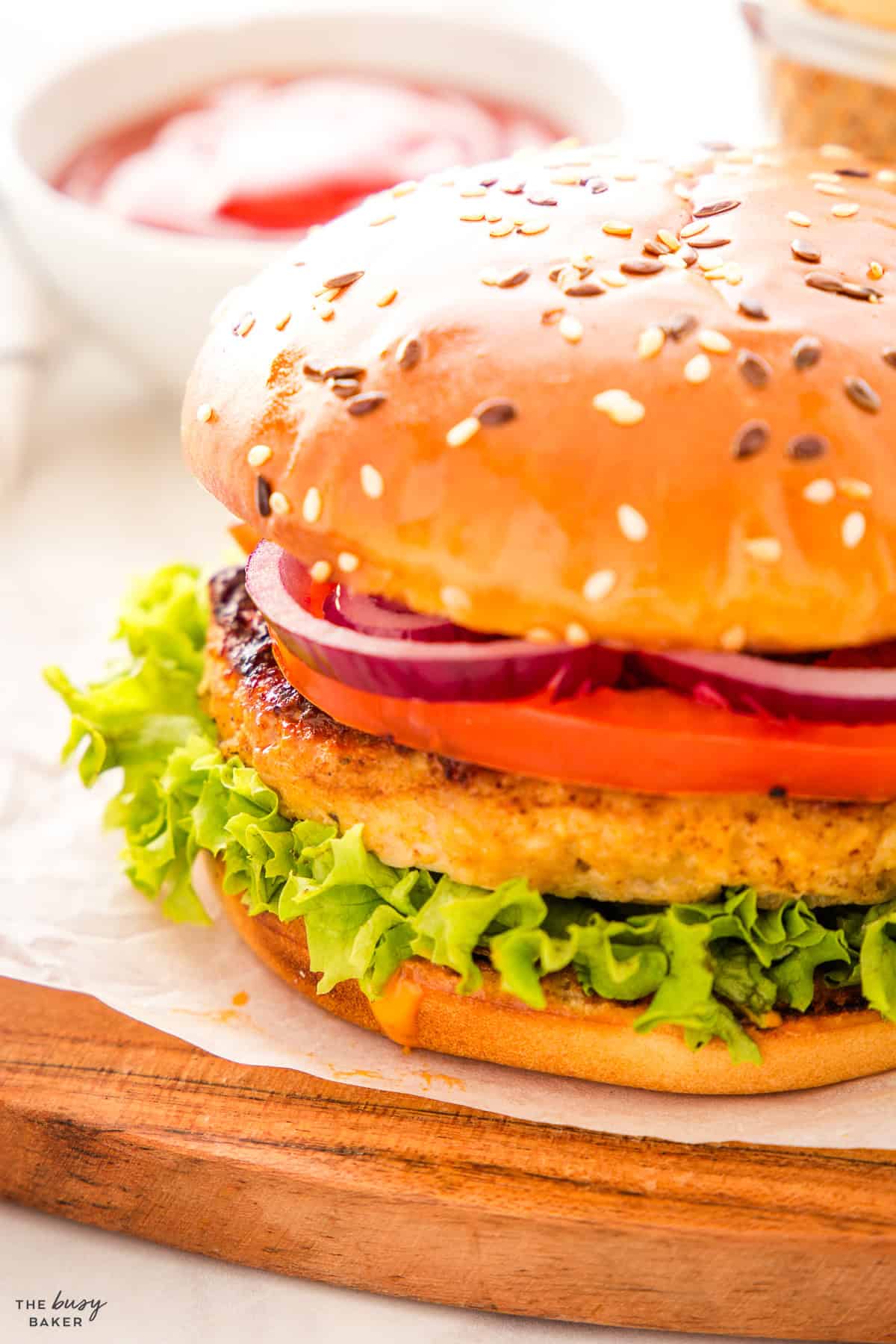 closeup image: burger on a wooden platter with fries and ketchup