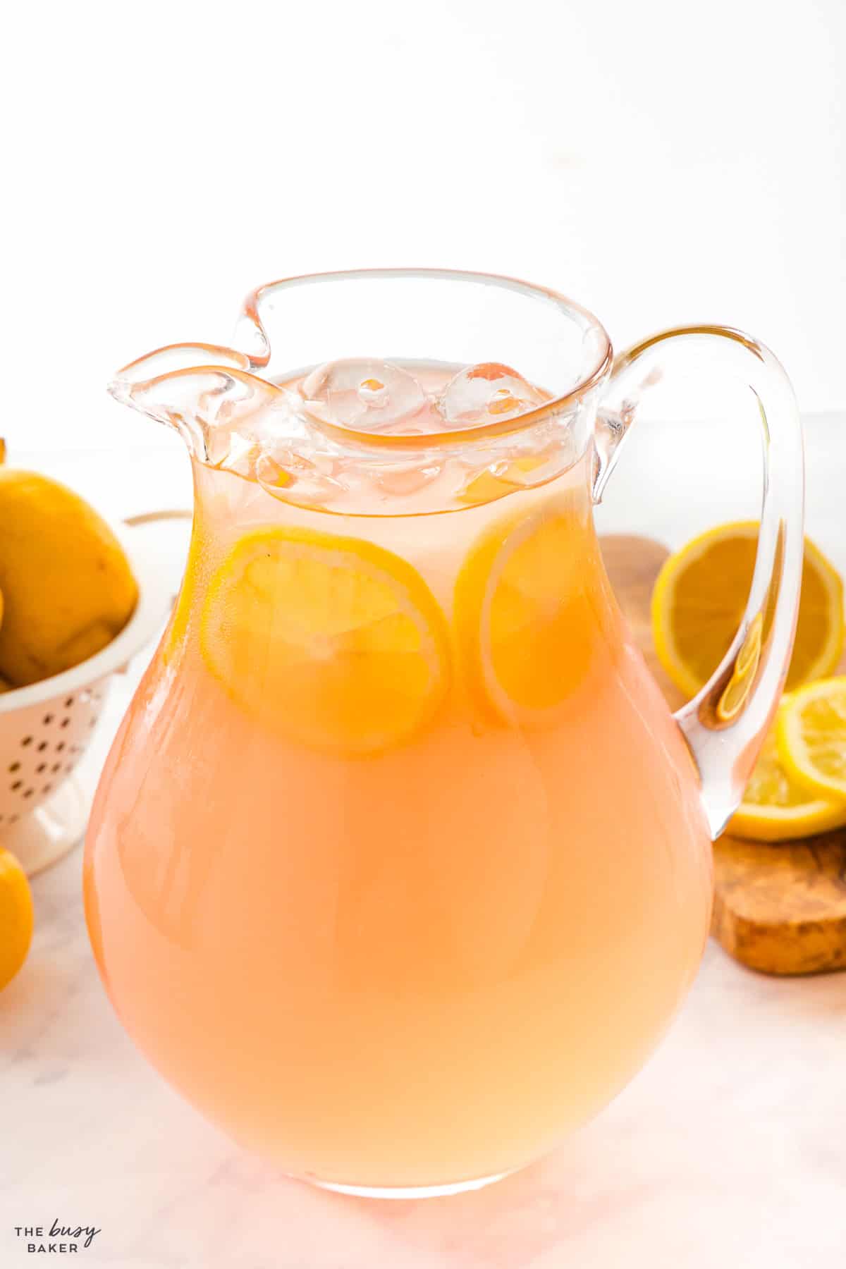 pitcher of pink lemonade with ice and lemon slices