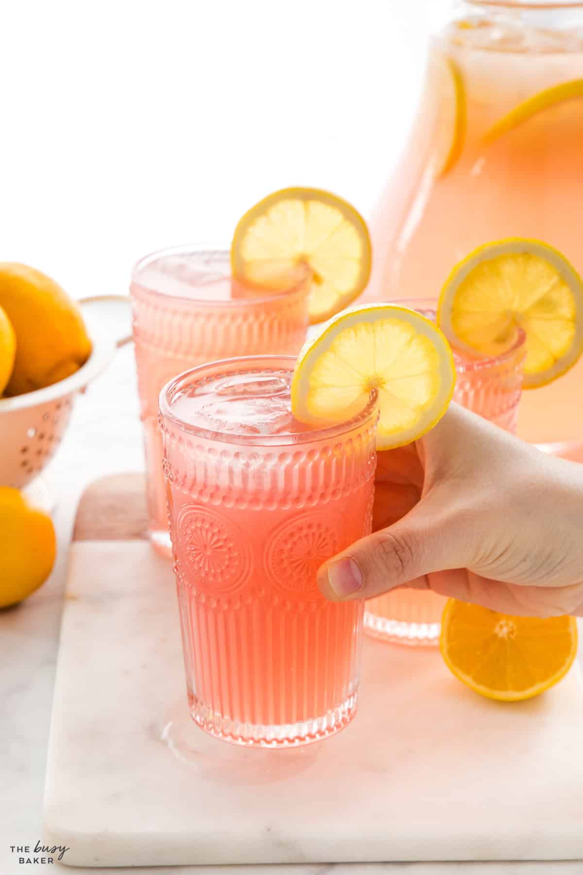hand holding a glass of pinnk lemonade