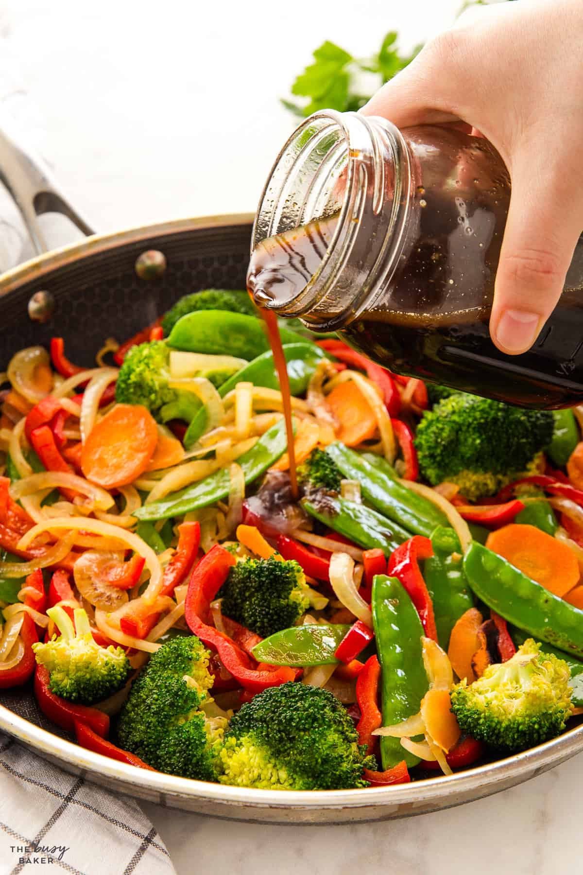 pouring stir fry sauce into a vegetable stir fry