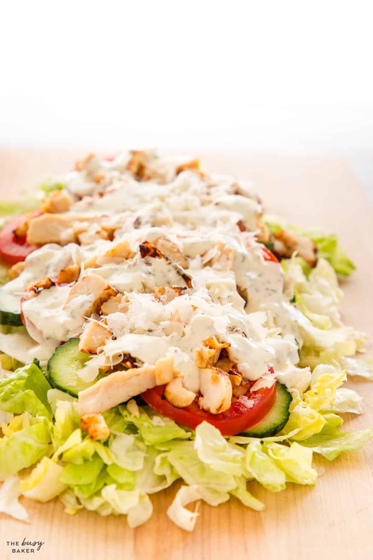 chicken caesar chopped salad with lettuce tomatoes, cucumbers, chicken and dressing