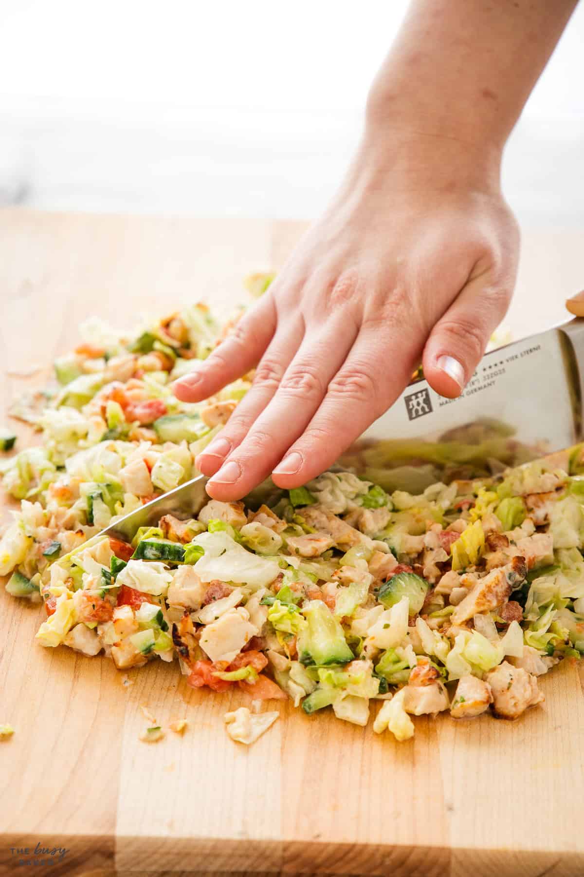chopped salad on a cutting board with a large knife