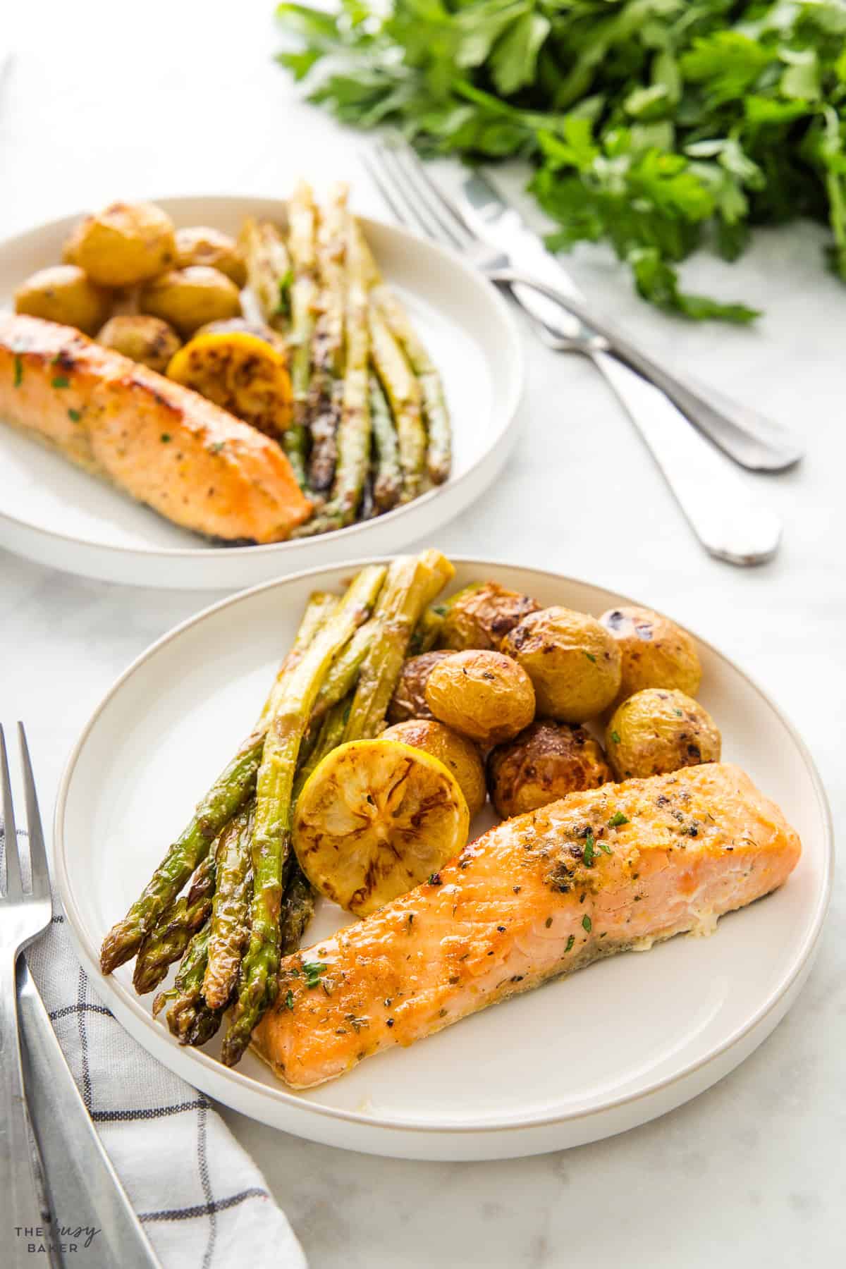 white plate with salmon, asparagus, lemon and potatoes