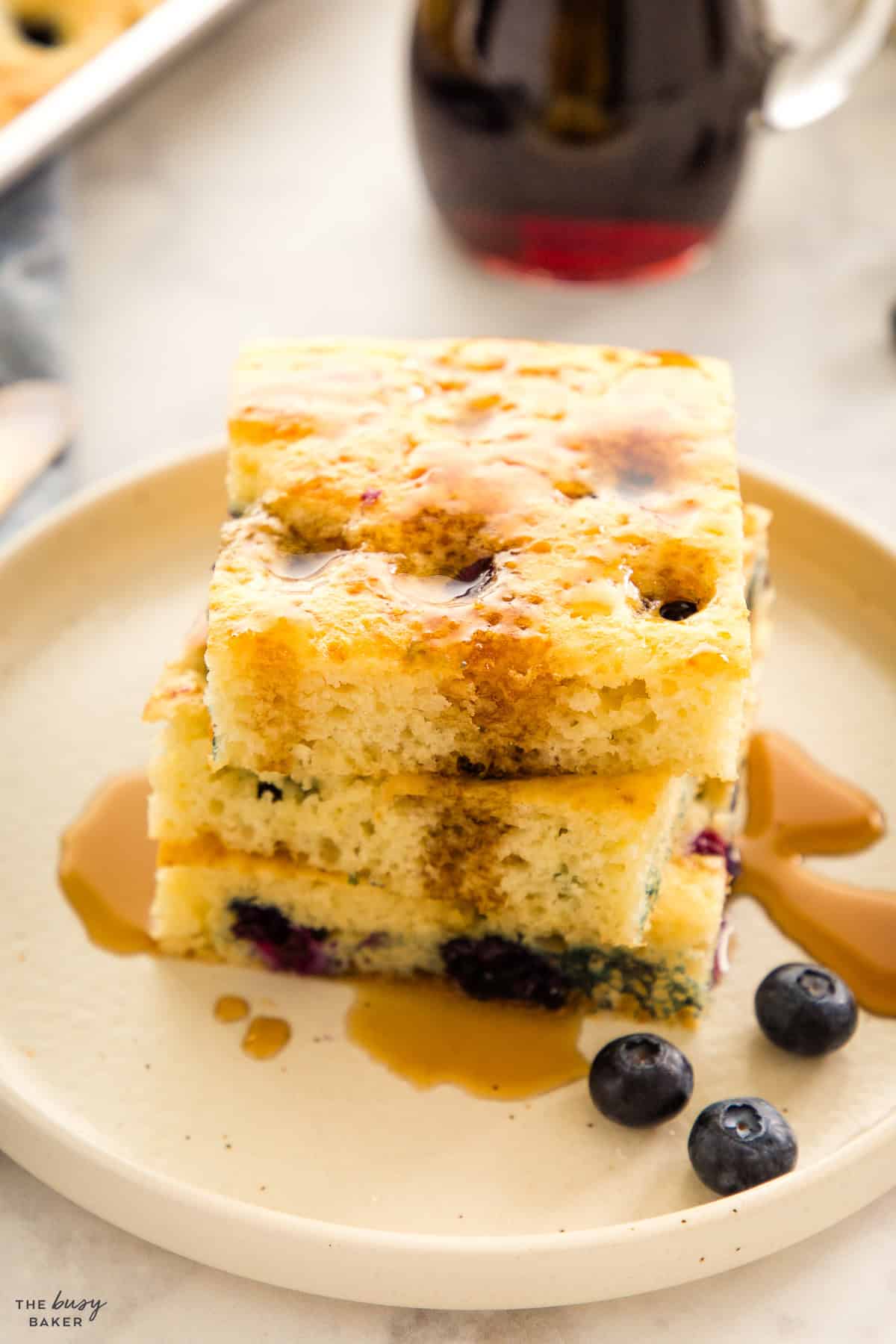 stack of sheet pan pancakes with maple syrup and blueberries