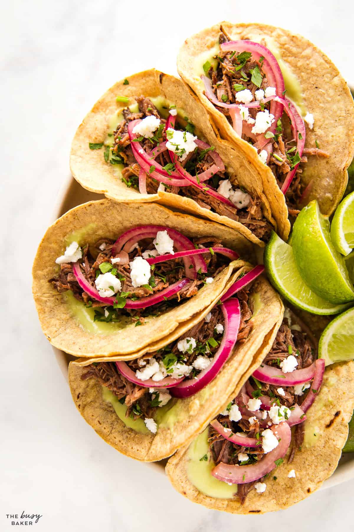 shredded beef tacos with lime and avocado and pickled onions