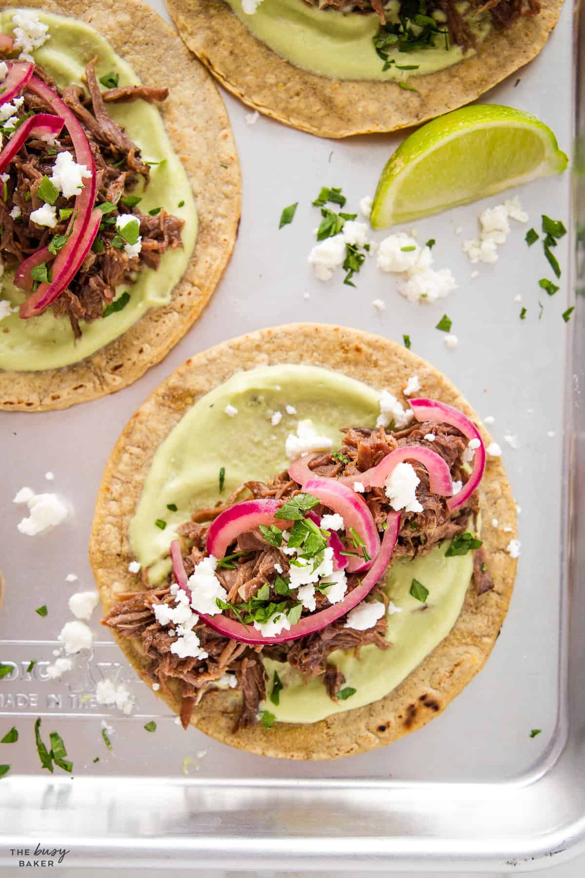 overhead image: beef taco with cheese, cilantro, avocado and pickled onions