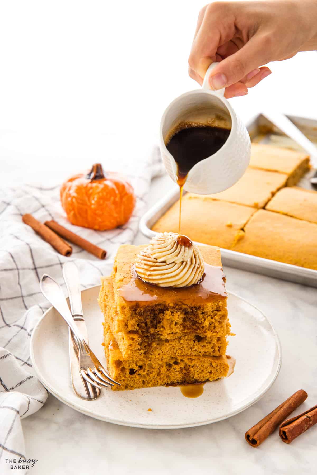 hand pouring maple syrup onto a stack of sheet pan pancakes