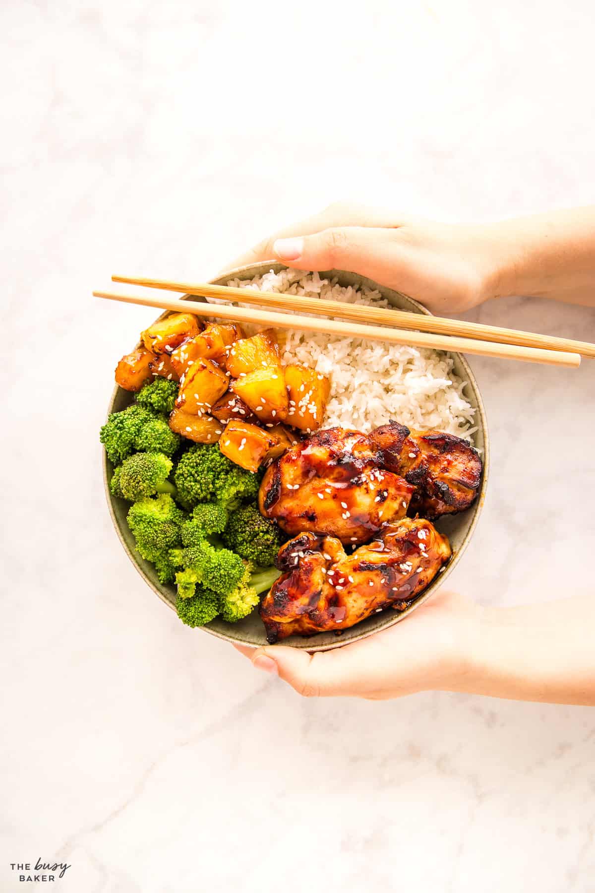 overhead image: healthy protein bowl with chicken, rice, pineapple and broccoli with teriyaki sauce
