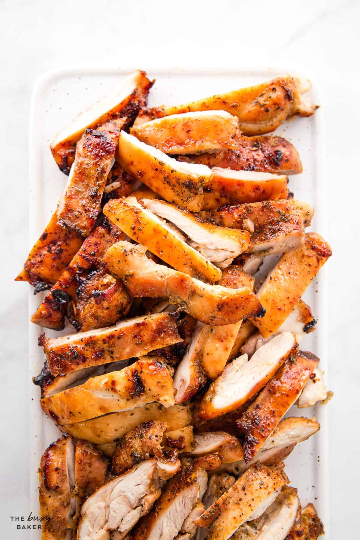 sliced grilled chicken on a white platter