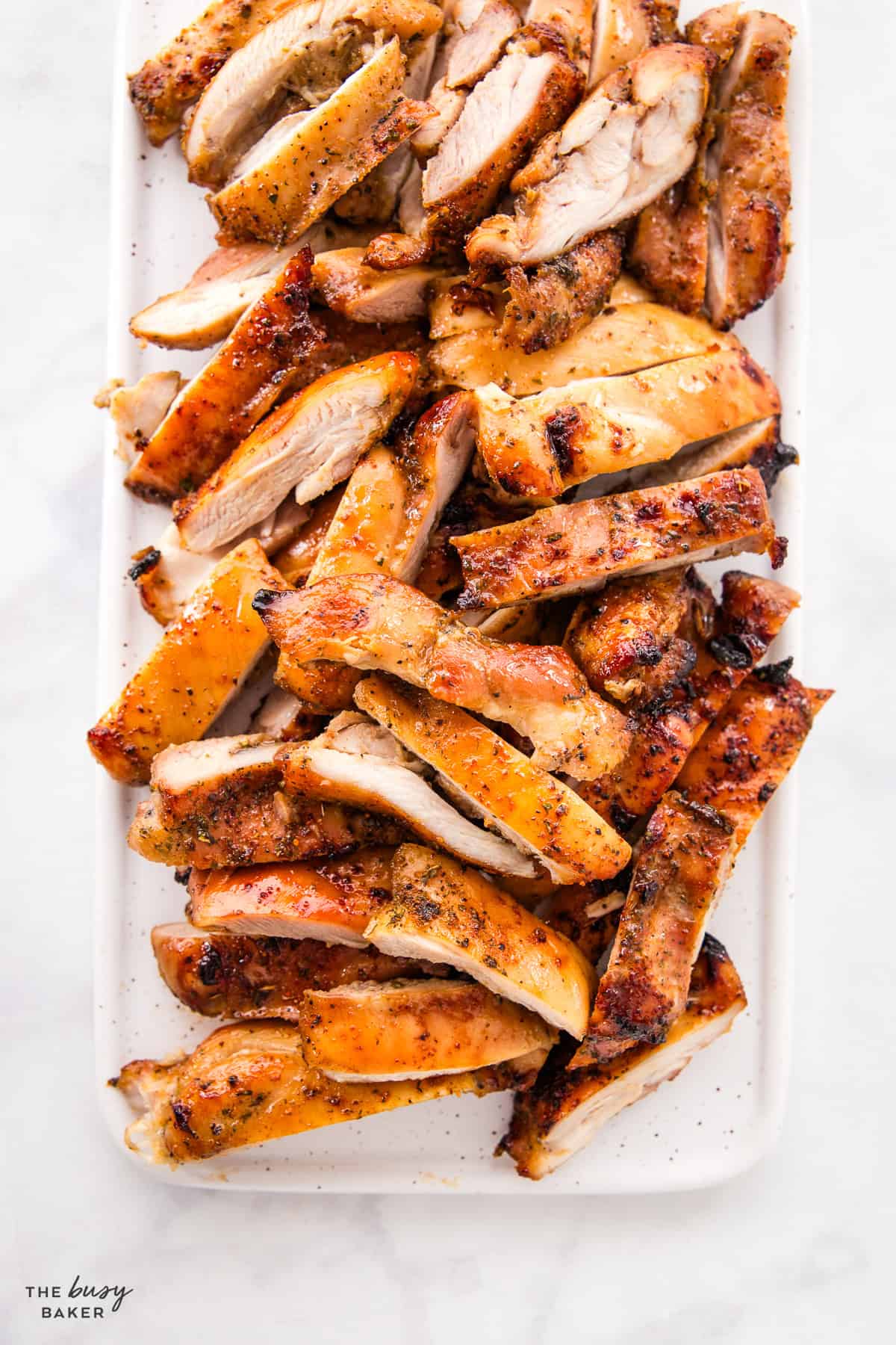 sliced chicken thighs on a white platter