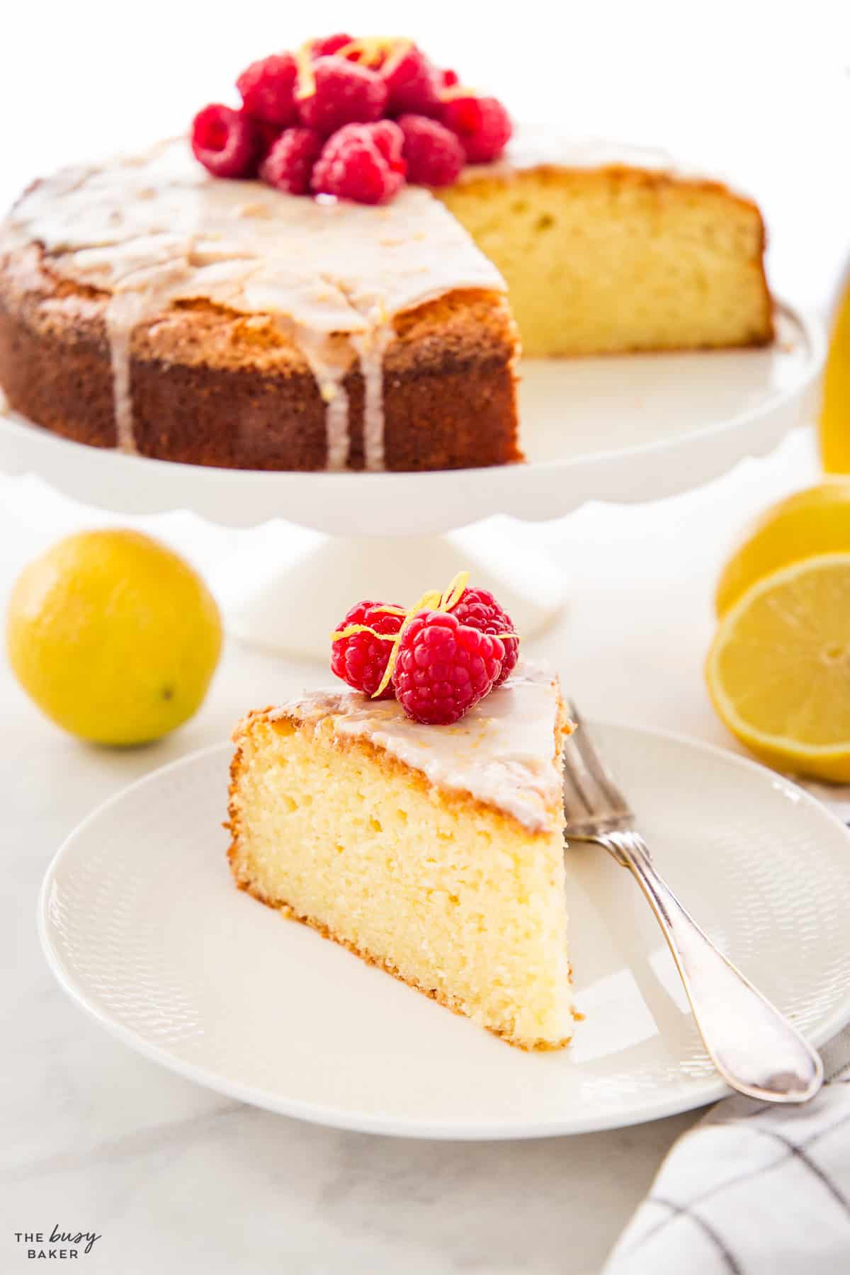slice of olive oil cake on a white plate with raspberries
