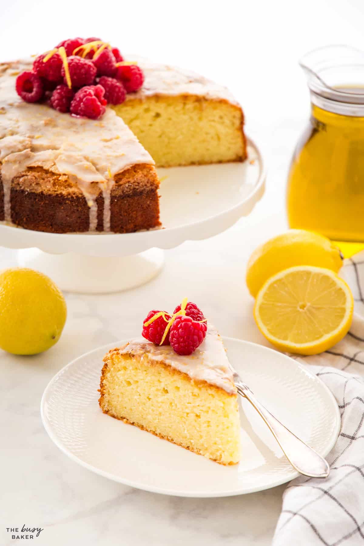 slice of olive oil cake with raspberries and lemon glaze