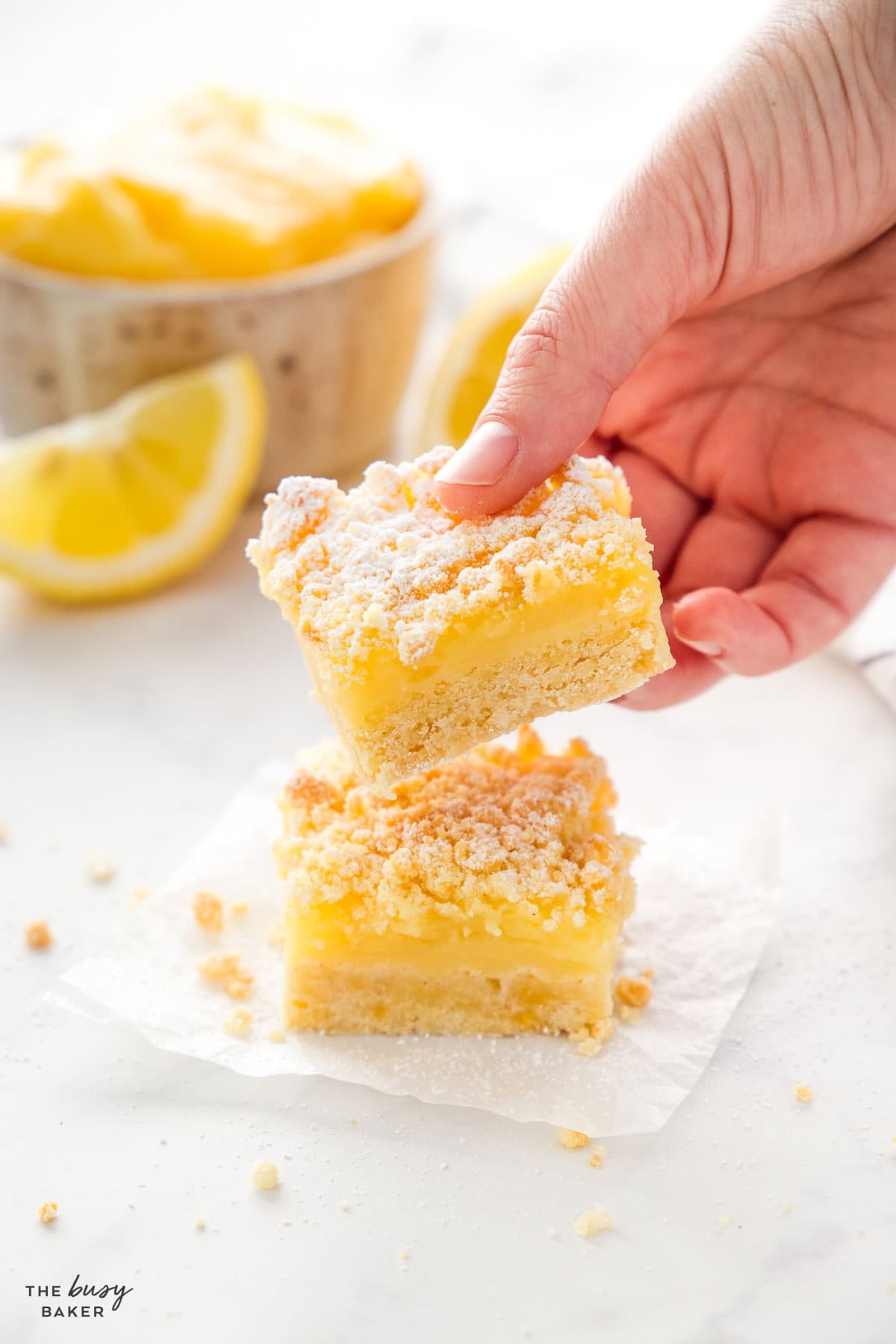 hand holding lemon bars with crumb topping