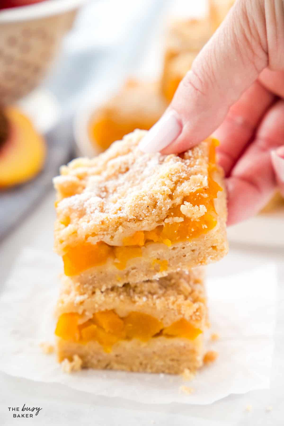 peach crumb bar in a hand with powdered sugar