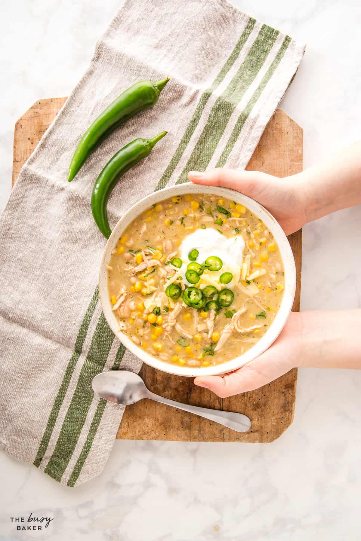 hands holding a bowl of white chicken chili