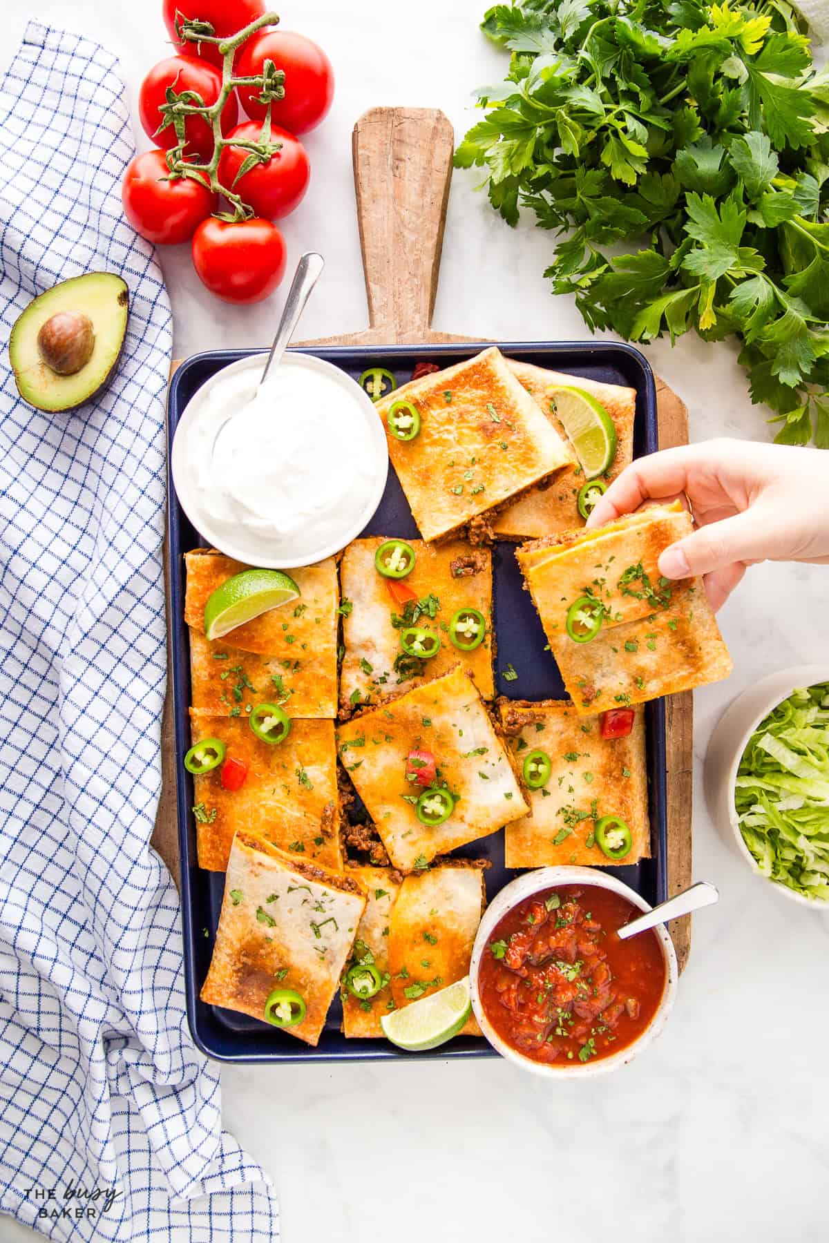 Sheet pan quesadillas cut into squares on a baking sheet with sour cream, salsa, and avocado