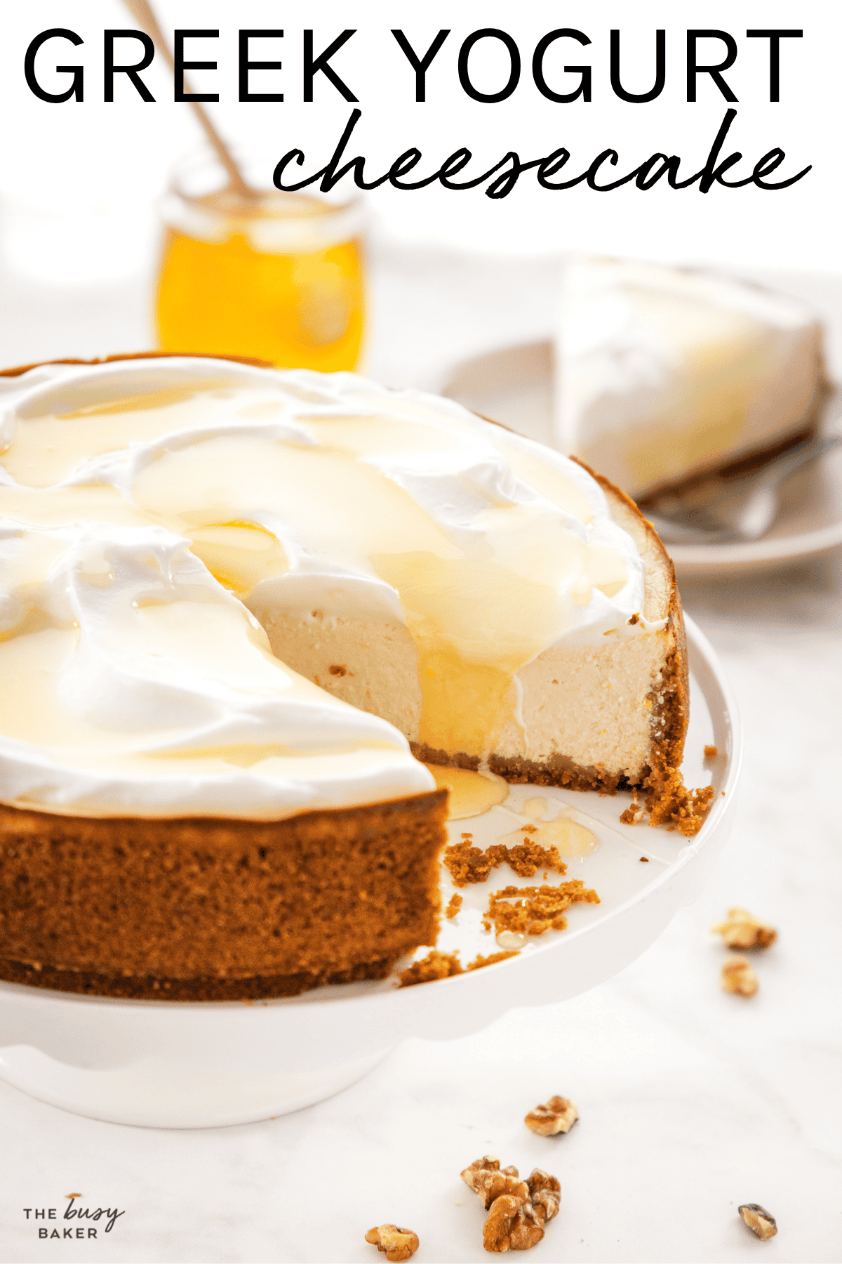 Healthy Greek yogurt cheesecake topped with whipped cream, honey, and walnuts on a white cake stand